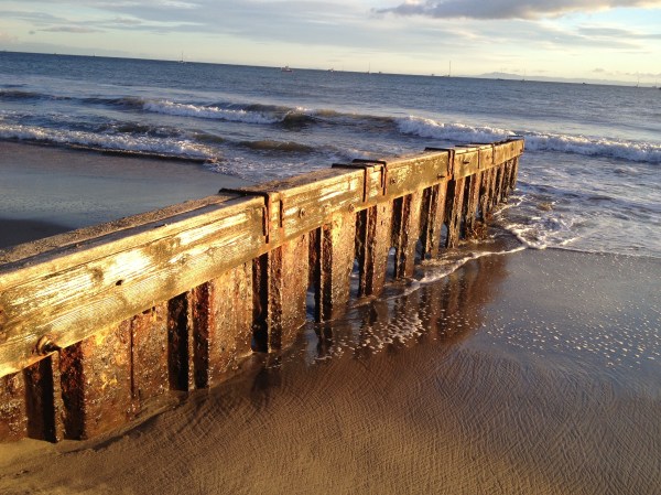 Eroded pilings meet the surf at East Beach, Santa Barbara, California